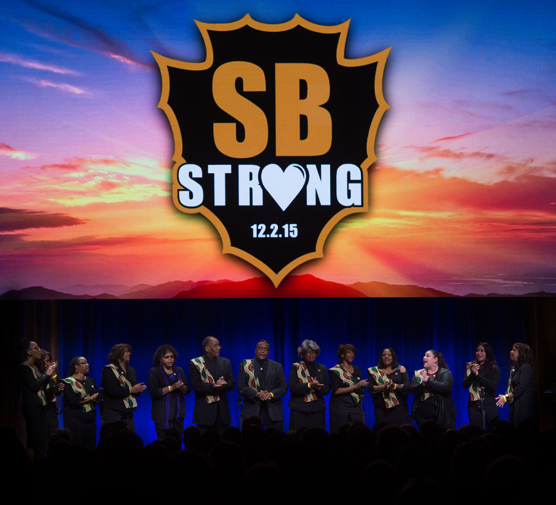 Members of a choir are onstage below an SB Strong image at the County Family Gathering